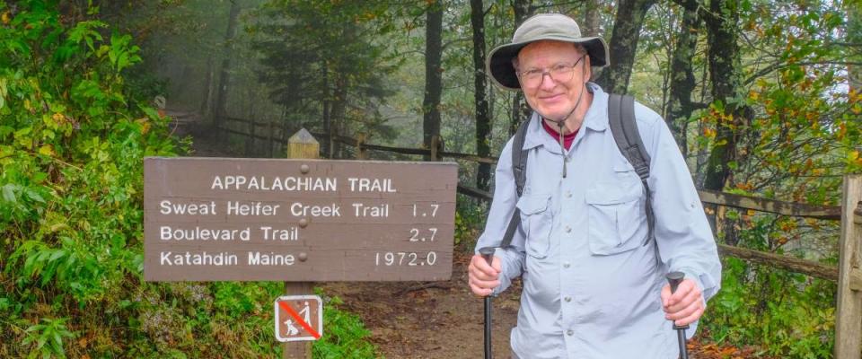 Smiling senior man standing next to Appalachian Trail sign