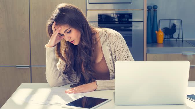 Woman doing paperwork with a laptop and digital tablet.