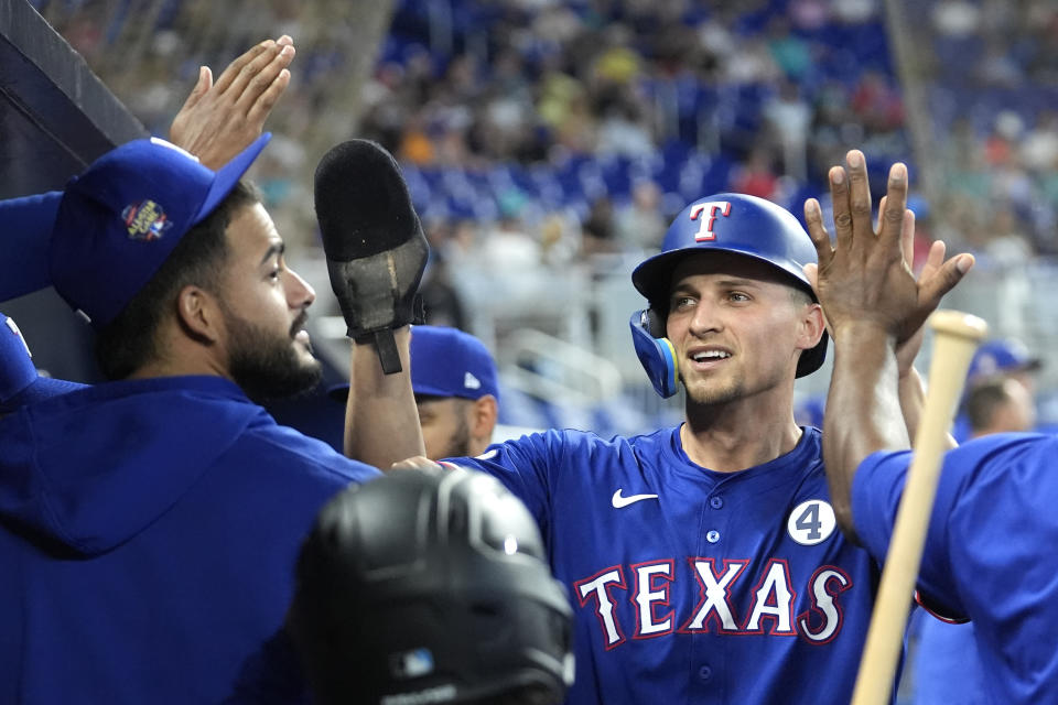 Texas Rangers' Corey Seager, right, is congratulated in the dugout after scoring on a single hit by Adolis Garcia during the first inning of a baseball game against the Miami Marlins, Sunday, June 2, 2024, in Miami. (AP Photo/Lynne Sladky)