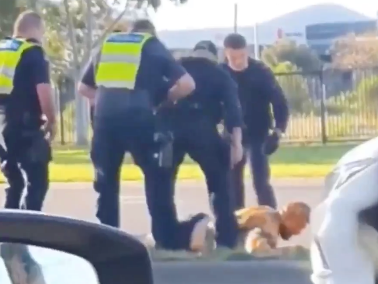 Victoria Police officers surround a man on the ground after hitting him with a police car (7News)