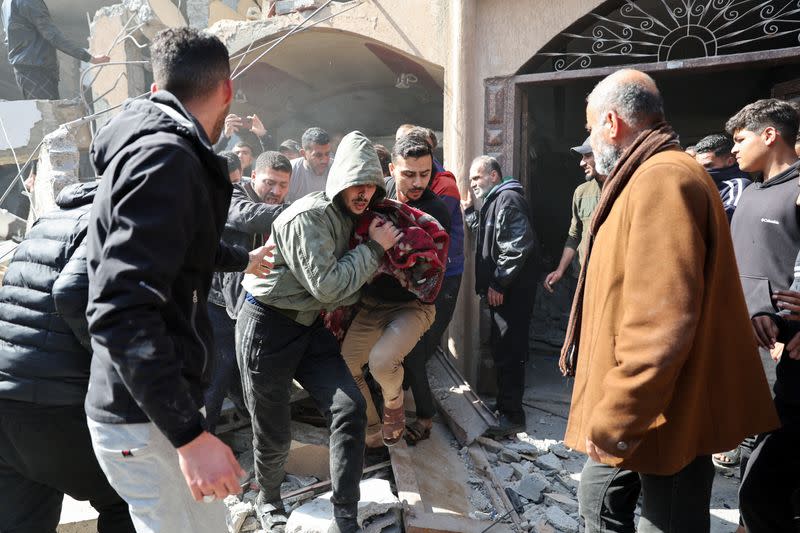 Palestinians attend to a casualty, at the sight of an Israeli strike on a house, in Rafah