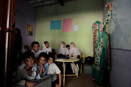 Students look out of the door as their teacher writes on the board at the Mashal Model school in Islamabad, Pakistan, September 26, 2017. REUTERS/Caren Firouz SEARCH "FIROUZ EDUCATION" FOR THIS STORY. SEARCH "WIDER IMAGE" FOR ALL STORIES.