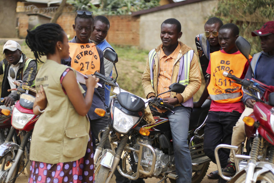 In this photo taken Friday, April 10, 2020, Martine Milonde, left, a Congolese community mobilizer who works with the aid group World Vision in Beni, eastern Congo, which became the epicenter of the Ebola outbreak, engages the public about coronavirus prevention. Congo has been battling an Ebola outbreak that has killed thousands of people for more than 18 months, and now it must also face a new scourge: the coronavirus pandemic. (AP Photo/Al-hadji Kudra Maliro)