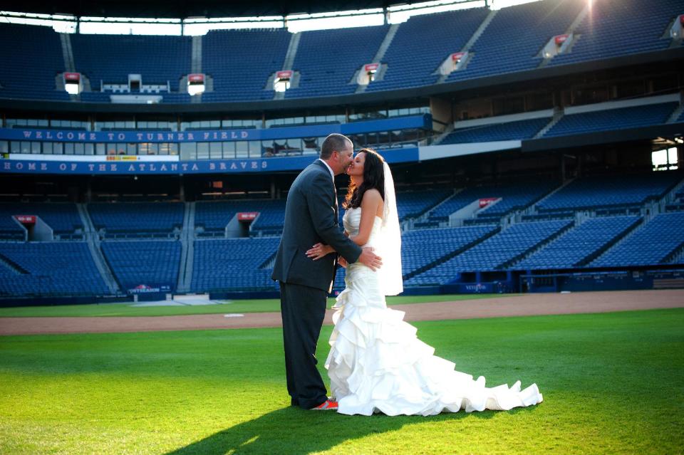 This Nov. 3, 2012 photo released courtesy of Trisha Benzine shows Nick and Trisha Benzine at their wedding held at Turner Field in Atlanta. Some couples, find that the massive stadiums where they enjoy hearing the crack of the bat can also be the perfect place to hear their beloved say, "I do." (AP Photo/Graceology Photography)