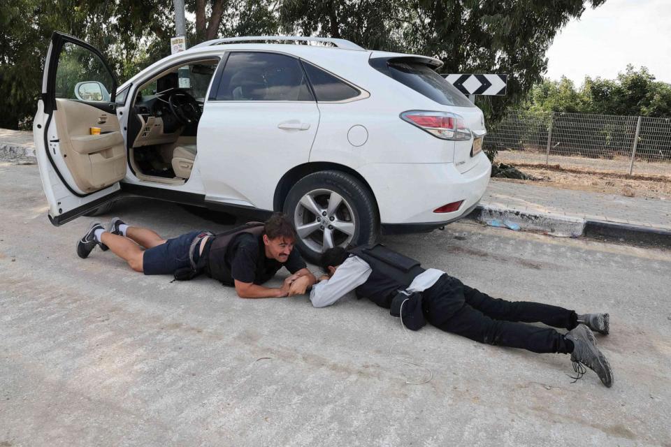 PHOTO: Israeli journalists take cover during a rocket attack from Gaza in the southern Israeli kibbutz of Kfar Aza near the border with the Palestinian territory, on Oct. 10, 2023. (Jack Guez/AFP via Getty Images)