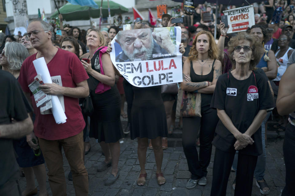 A woman holds a sign with a picture of the former President Luiz Inacio Lula da Silva, that reads in Portuguese "Without Lula is coup" during a protest against the military coup of 1964 in Rio de Janeiro, Brazil, Sunday, March 31, 2019. Brazil's president Jair Bolsonaro, a former army captain who waxes nostalgic for the 1964-1985 dictatorship, asked Brazil's Defense Ministry to organize "due commemorations" on March 31, the day historians say marks the coup that began the dictatorship. (AP Photo/Leo Correa)