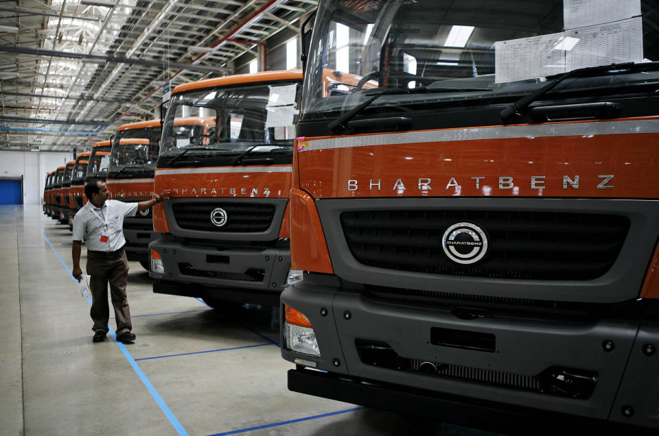 A Daimler AG official examines Bharat-Benz trucks displayed during the opening ceremony of Daimler's new factory in Oragadam at Kancheepuram district 60 kilometers (38 miles) from Chennai, India, Wednesday, April 18, 2012. The German auto maker will start building trucks at the new factory beginning in the third quarter. The factory will initially have a capacity to make 36,000 trucks a year and raise it to 72,000 units, the company said. (AP Photo/Arun Shankar)