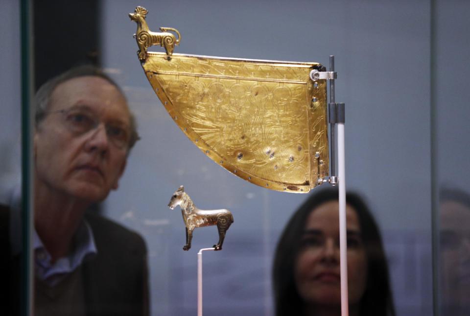 Visitors look at a Viking horse statuette and a decorated warship weathervane at a new exhibition entitled 'Vikings: Life and Legend' at the British Museum in central London, Tuesday, March 4, 2014. The new exhibition strives to make people think again about the Scandinavian pillagers who raided and struck terror into English villages. The exhibition aims to show how Viking energy and ideas re-drew the map of the world, through the presentation of their ships, their weapons, their crafts, their words and even their skeletons. (AP Photo/Lefteris Pitarakis)