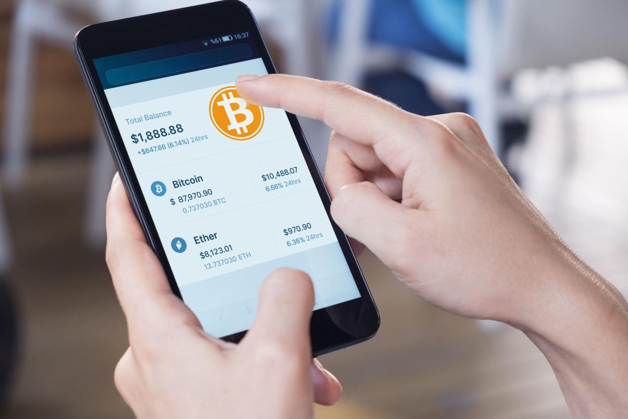 Woman using a smart phone displaying a bitcoin wallet screen.