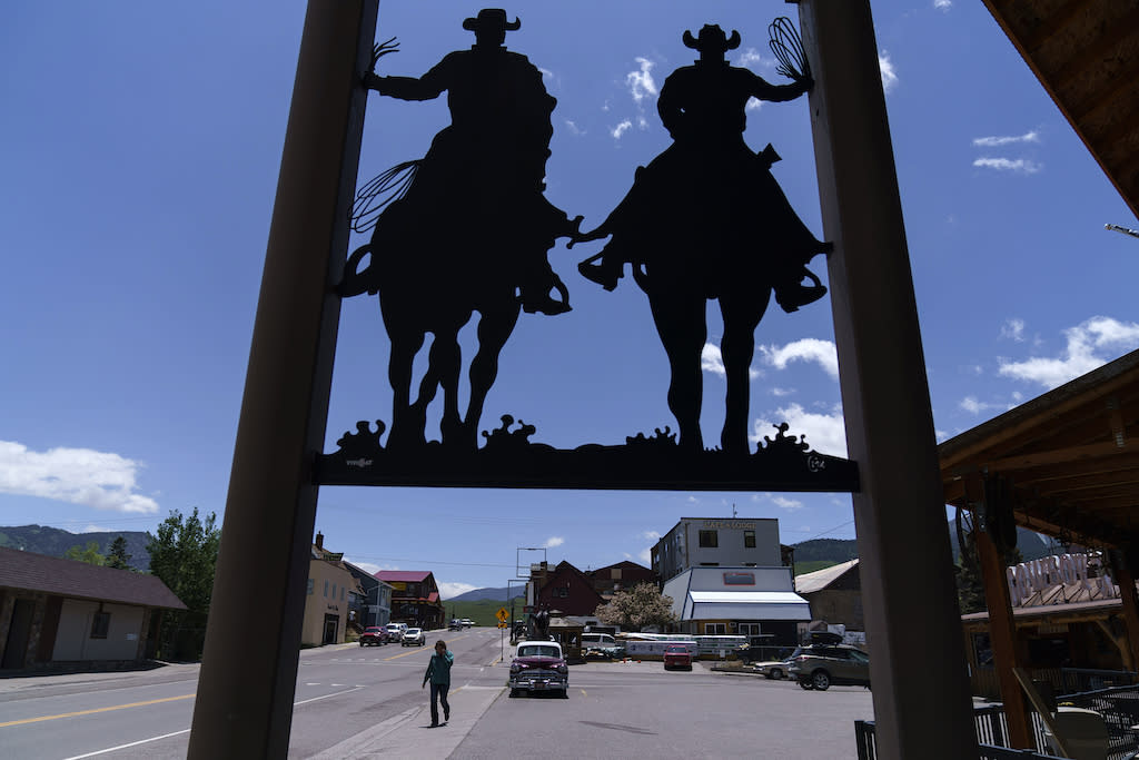 A person walking in the street, with carved silhouettes of cowboys above.