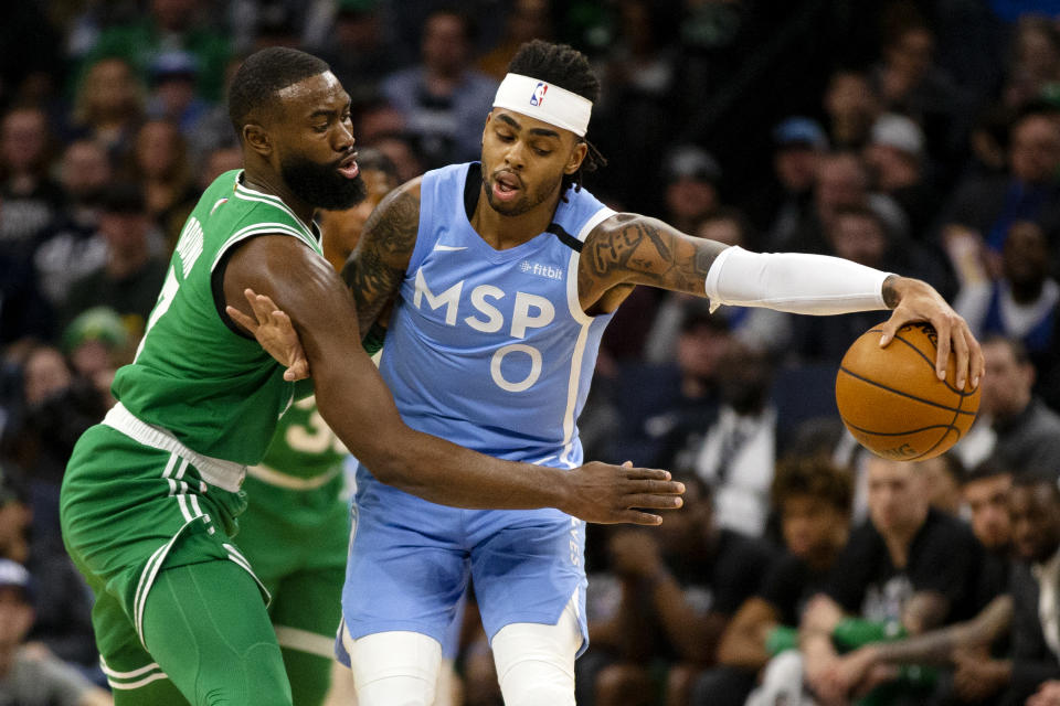 Minnesota Timberwolves guard D'Angelo Russell (0) blocks the reach of Boston Celtics guard Jaylen Brown (7) in the first quarter of an NBA basketball game Friday, Feb. 21, 2020, in Minneapolis. (AP Photo/Andy Clayton-King)