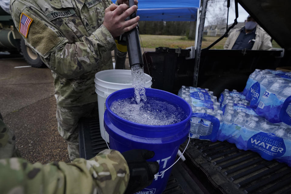 Mississippi Army National Guard Sgt. Chase Toussaint with the Maneuver Area Training Equipment Site of Camp Shelby, right, fills 5-gallon buckets with non-potable water, Monday, March 1, 2021, at a Jackson, Miss., water distribution site on the New Mt. Zion Missionary Baptist Church parking lot. Water for flushing toilets was being distributed at seven sites in Mississippi's capital city — more than 10 days after winter storms wreaked havoc on the city's water system because the system is still struggling to maintain consistent water pressure, authorities said. (AP Photo/Rogelio V. Solis)