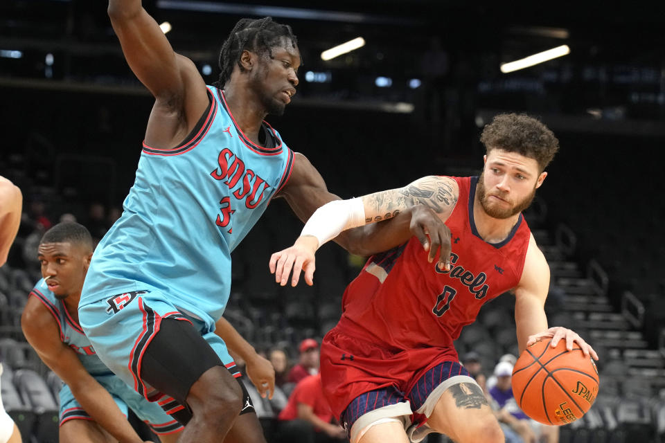 St. Mary's guard Logan Johnson (0) drives on San Diego State forward Nathan Mensah during the first half of an NCAA college basketball game at the Jerry Colangelo Classic, Saturday, Dec. 10, 2022, in Phoenix. (AP Photo/Rick Scuteri)