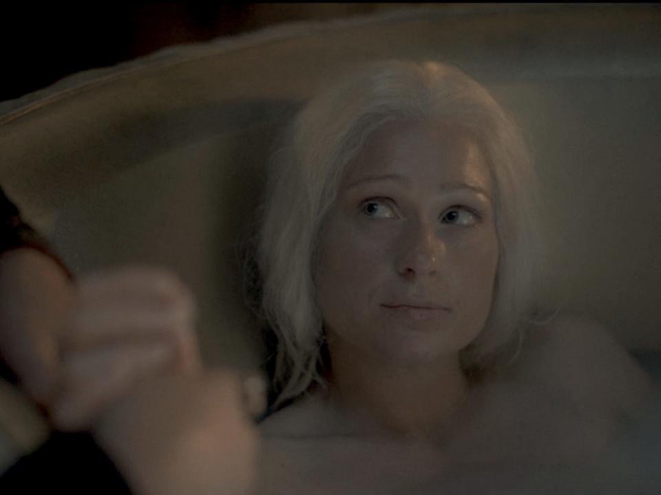 A woman with silvery-blonde hair sitting in a bathtub.