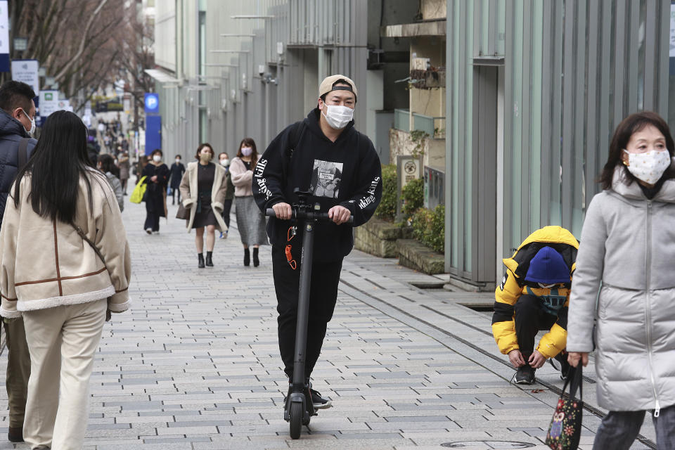 A man wearing a face mask to protect against the spread of the coronavirus rides a scooter along a sidewalk in Tokyo, Tuesday, Feb. 2, 2021. (AP Photo/Koji Sasahara)