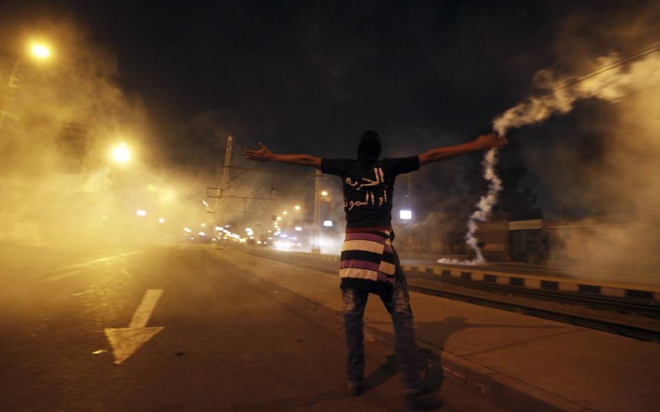 A protester shouts at police as smoke rises around him (Reuters)
