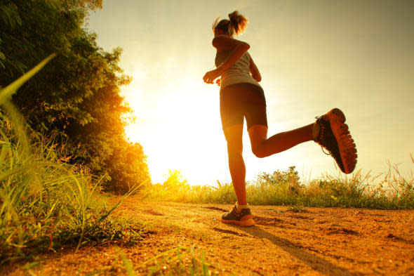 Young lady running on a rural road during sunset