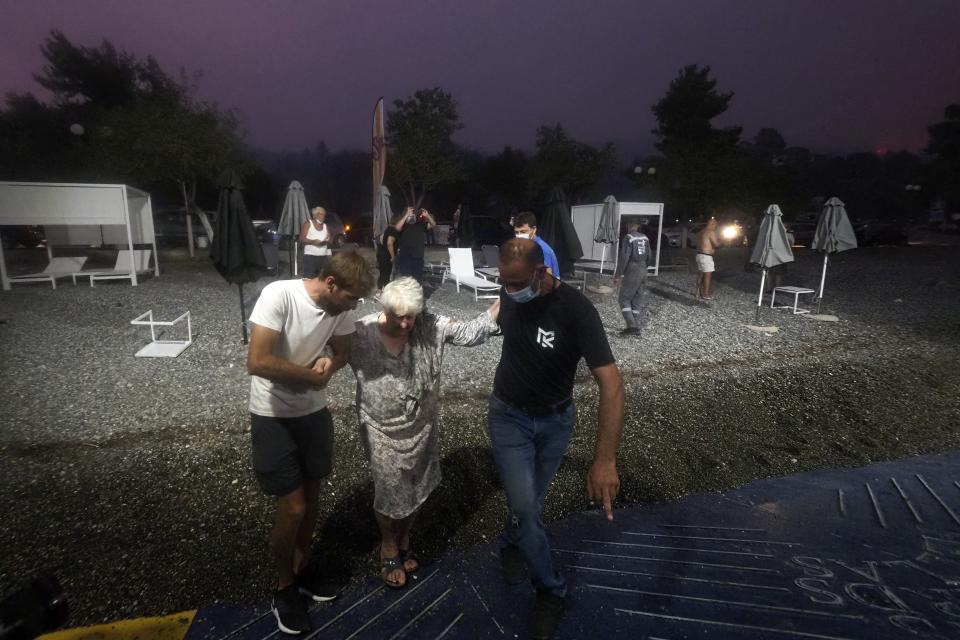 People embark a ferry during an evacuation from Kochyli beach as wildfire approaches near Limni village on the island of Evia, about 160 kilometers (100 miles) north of Athens, Greece, Friday, Aug. 6, 2021. Thousands of people fled wildfires burning out of control in Greece and Turkey on Friday, including a major blaze just north of the Greek capital of Athens that claimed one life, as a protracted heat wave left forests tinder-dry and flames threatened populated areas and electricity installations. (AP Photo/Thodoris Nikolaou)