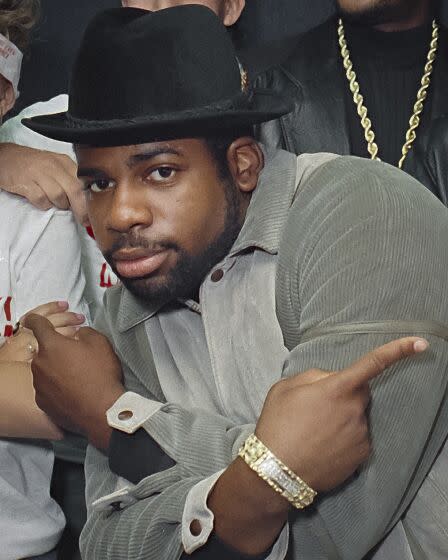 Run-DMC's Jam Master Jay wearing a hat as he crosses his arms in an X and points his index fingers