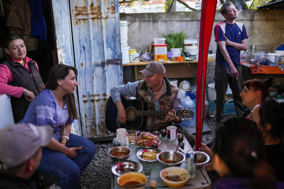 Volunteers sing Ukrainian patriotic songs after having lunch at the end of their shift at a facility producing material for Ukrainian soldiers in Zaporizhzhia, Ukraine, Friday, May 6, 2022. An old industrial complex in the southeastern Ukrainian riverside city of Zaporizhzhia has become a hive of activity for volunteers producing everything from body armor to camouflage nets, anti-tank obstacles to heating stoves and rifle slings for Ukrainian soldiers fighting the Russian invasion. (AP Photo/Francisco Seco)