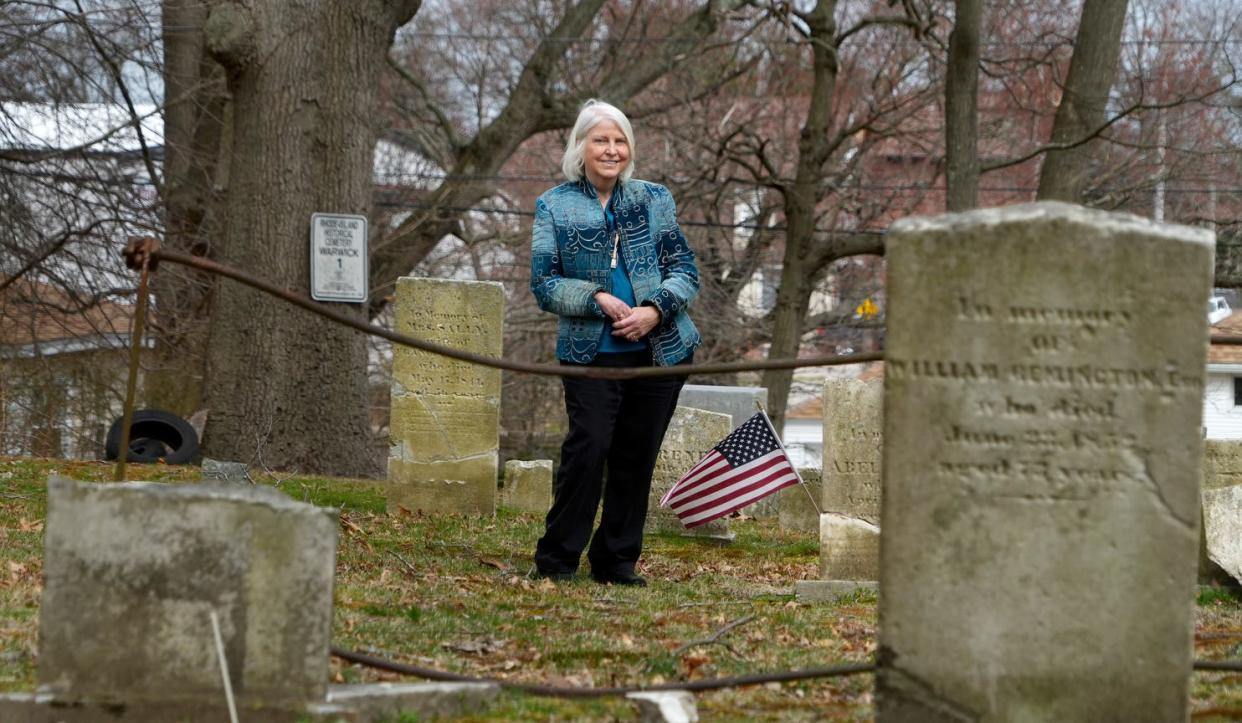 Pegee Malcolm, chair of the state's Historical Cemetery Commission, stands among the stones in a historical cemetery in Warwick.