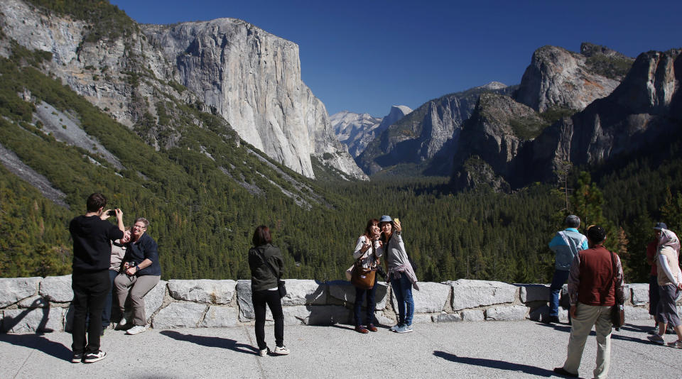 Visitors at Tunnel View, like Kaori Nishimura and Eriko Kuboi, from Japan, center facing, flock to the reopening of Yosemite National Park, Calif., Thursday, Oct. 17, 2013. Tunnel View is a scenic vista which shows off El Capitan, Half Dome and Bridalveil Fall. The park reopened Wednesday night with the end of the 16-day partial government shutdown. (AP Photo/Gary Kazanjian)