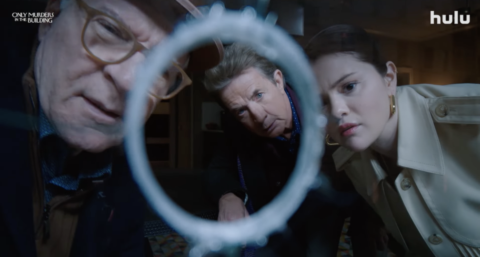 Steve Martin, Martin Short, and Selena Gomez inspect a piece of broken glass in a scene from Hulu's "Only Murders in the Building."