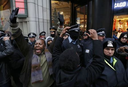 Demonstators hold their hands up in front of Chicago Police officers during protest of last year's shooting death of black teenager Laquan McDonald by a white policeman and the city's handling of the case in the downtown shopping district of Chicago, Illinois, November 27, 2015. REUTERS/Jim Young