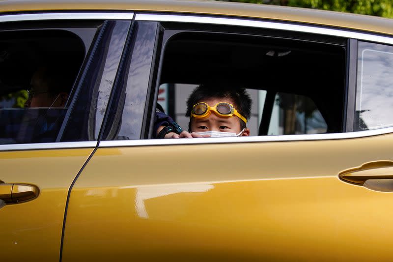 A boy wearing a face mask is seen inside a car after the lockdown was lifted in Wuhan