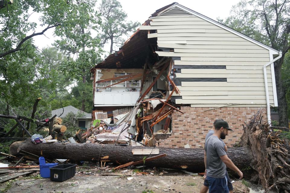 Personas se reúnen fuera de una residencia en Rustic Canyon Trail en donde Maria Laredo, de 74 años, falleció después de que un árbol cayó sobre su alcoba en el segundo piso durante el huracán Beryl, el lunes 8 de julio de 2024, en Houston. (Melissa Phillip/Houston Chronicle via AP)