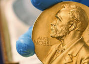 FILE - In this April 17, 2015 file photo shows a gold Nobel Prize medal. Americans Paul R. Milgrom and Robert B. Wilson have won the Nobel Prize in economics for "improvements to auction theory and inventions of new auction formats." it was announced Monday Oct. 12, 2020. (AP Photo/Fernando Vergara, File)