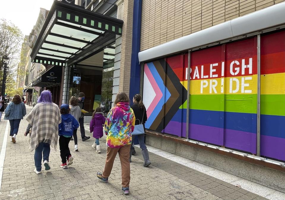 A family walks by an LGBTQ pride mural in downtown Raleigh, North Carolina, just a few blocks away from the Legislative Building, on Nov. 16, 2022. Statehouse victories for Republicans this month are resonating for transgender people as they mark Transgender Day of Remembrance Sunday, Nov. 20, 2022. (AP Photo/Hannah Schoenbaum)