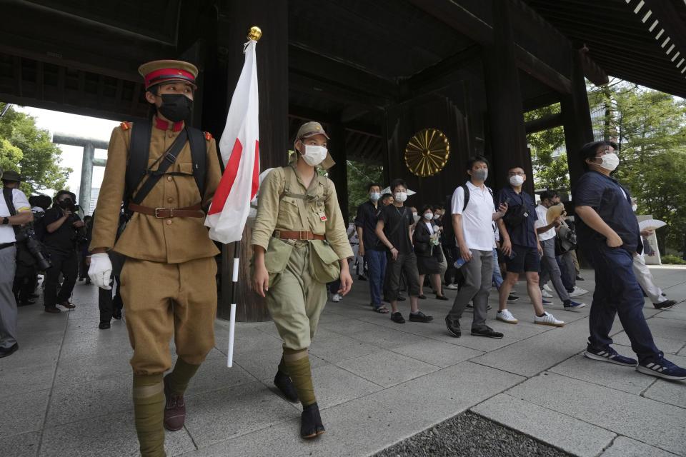 Visitors in old Japanese Imperial army uniforms enter Yasukuni Shrine, which honors Japan's war dead, Monday, Aug. 15, 2022, in Tokyo. Japan marked the 77th anniversary of its World War II defeat Monday. (AP Photo/Eugene Hoshiko)