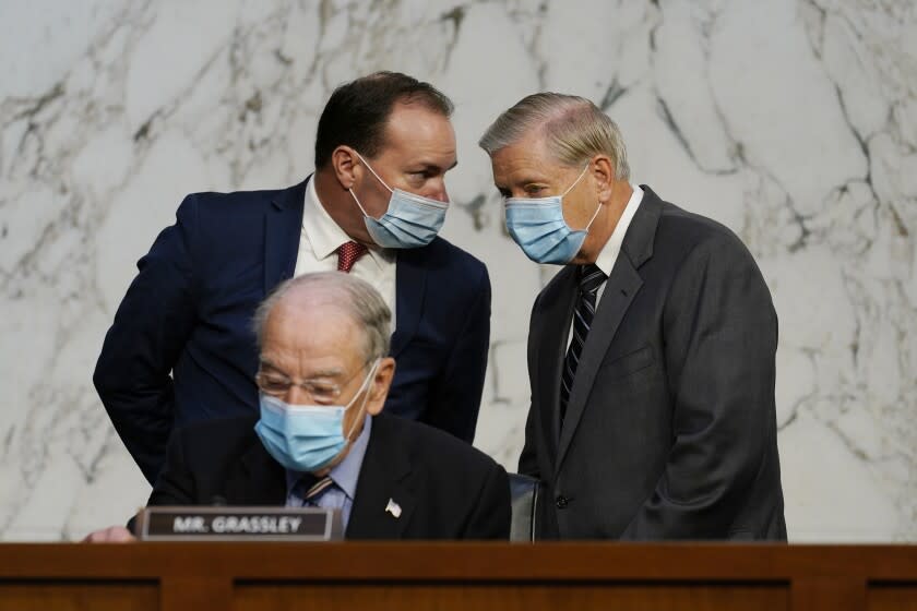 Senate Judiciary Committee Chairman Sen. Lindsey Graham, standing right, talks to Sen. Mike Lee, R-Utah., as Sen. Charles Grassley, R-Iowa, sits below, before a confirmation hearing for Supreme Court nominee Amy Coney Barrett before the Senate Judiciary Committee, Monday, Oct. 12, 2020, on Capitol Hill in Washington. (AP Photo/Susan Walsh, Pool)