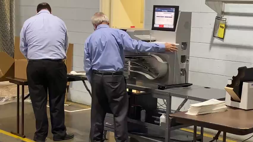 A Rhode Island Board of Elections employee, left, works with a technician to process paper ballots at the board's headquarters in Cranston on Election Day.
