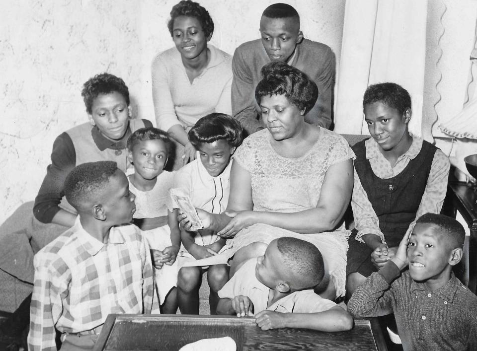 Helen Arnold holds the $350 she received from a Secret Santa in 1960. From left, her children are John, 12, Mona, 14, Donna, 5, Cathy, 19, Carla, 8, Royal, 16, Gerald, 7, Gale, 13, and Gary, 10. The children attended Bryan Elementary, Jennings Junior High and North High.