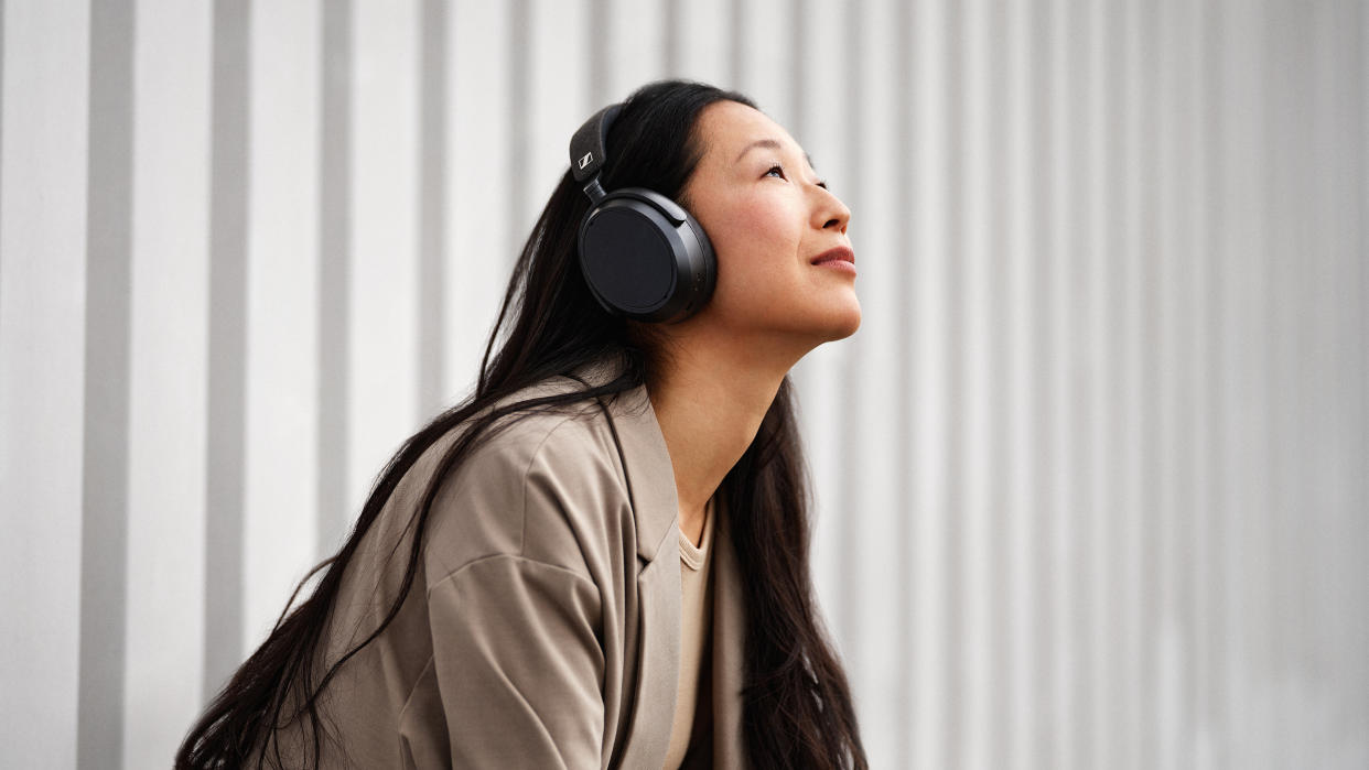  A woman wearing the Sennheiser Momentum 4 Wireless over-ear headphones 