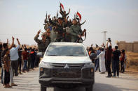 In this photo released by the Syrian official news agency SANA, people welcome Syrian troops as they enter the town of Ein Issa, north of Raqqa, Syria, Monday, Oct 14, 2019. Syrian troops moved east from Aleppo province to Raqqa where state media said they had reached Ein Issa. Heavy fighting the previous day there reached a Kurdish-run displaced-person camp that is home to some 12,000 people, including around 1,000 wives and widows of IS fighters and their children. Hundreds are believed to escaped amid the chaos. (SANA via AP)