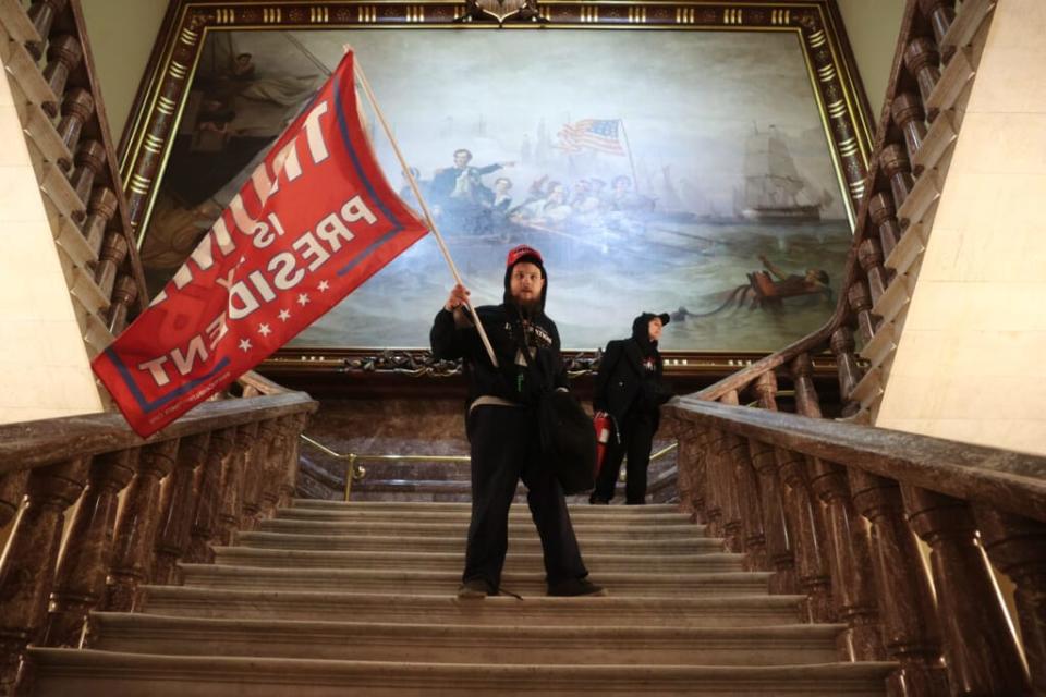 WASHINGTON, DC – JANUARY 06: A protester holds a Trump flag inside the US Capitol Building near the Senate Chamber on January 06, 2021 in Washington, DC. Congress held a joint session today to ratify President-elect Joe Biden’s 306-232 Electoral College win over President Donald Trump. A group of Republican senators said they would reject the Electoral College votes of several states unless Congress appointed a commission to audit the election results. (Photo by Win McNamee/Getty Images)