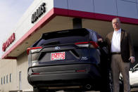 Scott Adams, owner of Adams Toyota, stands with a hybrid Toyota Rav4 at his dealership Tuesday, Dec. 12, 2023, in Lee's Summit, Mo. A typical hybrid costs somewhat more than its gasoline counterpart. A Toyota RAV4 hybrid with all-wheel-drive, for example, starts at $32,825, $1,600 more than a comparable gas version. (AP Photo/Charlie Riedel)