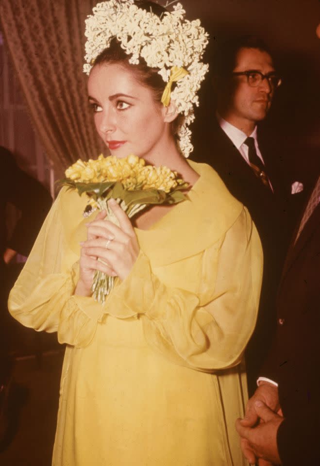 <p>Precisamos mostrar também o vestido amarelo canário que ela escolheu para se casar com Richard Burton (seu 5o marido). Desta vez ela optou por um penteado dramático com jacintos e lírios no cabelo. [<i>Foto: Getty</i>]</p>