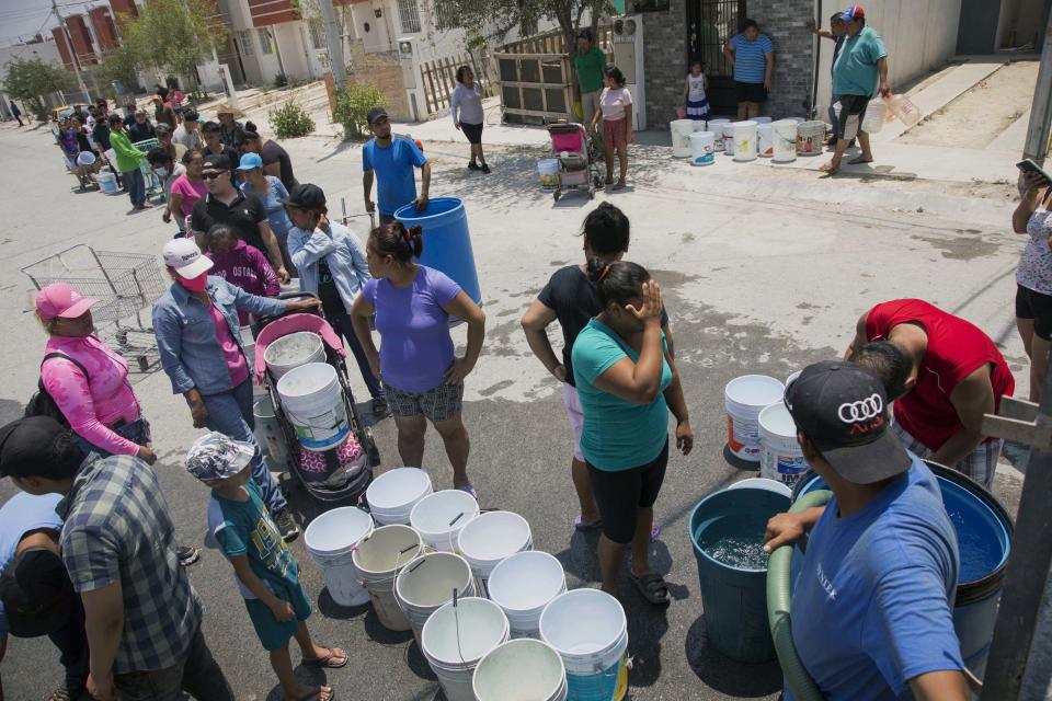 Los vecinos hacen cola para recoger agua limpia de un camión cisterna en el municipio de García, al noroeste del área metropolitana de Monterrey, estado de Nuevo León, México, el 8 de junio de 2022. (Foto de JULIO CESAR AGUILAR/AFP vía Getty Images)
