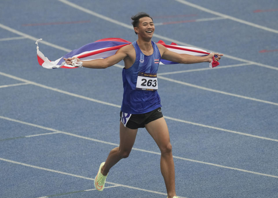 Thailand's Soraoat Dapbang celebrates with his country's flag after winning in the men's 100-meter dash final at the 32nd Southeast Asian Games in Phnom Penh, Cambodia, Friday, May 12, 2023. (AP Photo/Tatan Syuflana)