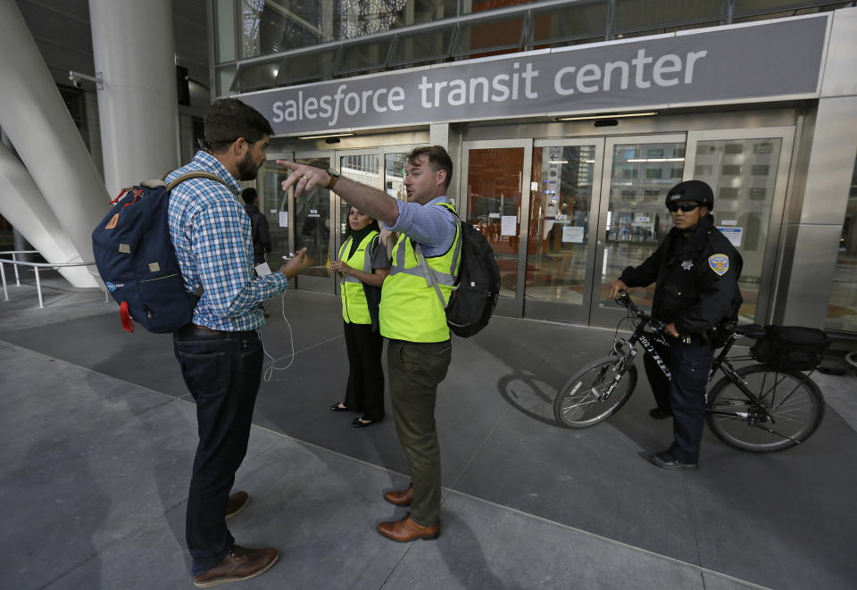 Mike Eshleman, with AC Transit, directs people away from the Salesforce Transit Center following its closure, Tuesday, Sept. 25, 2018, in San Francisco. San Francisco officials shut down the city's celebrated new $2.2 billion transit terminal Tuesday after discovering a crack in a support beam under the center's public roof garden. Coined the "Grand Central of the West," the Salesforce Transit Center opened in August near the heart of downtown after nearly a decade of construction. It was expected to accommodate 100,000 passengers each weekday, and up to 45 million people a year. (AP Photo/Eric Risberg)