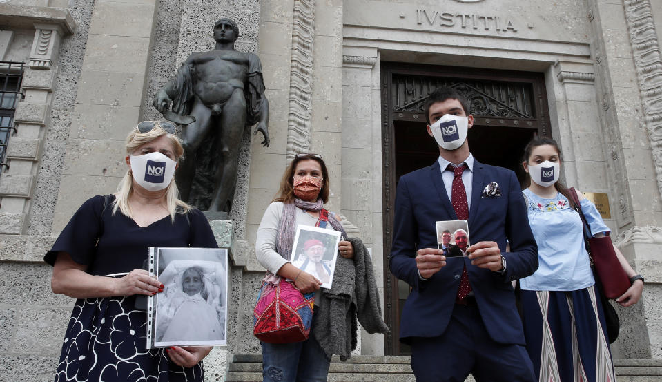 FILE - In this June 10, 2020 file photo, members of Noi Denunceremo (We will denounce) Facebook group, from left, Laura Capella, Nicoletta Bosica, Stefano Fusco and Arianna Dalba holds pictures of their relatives, victims of COVID-19, as they stand in front of Bergamo's court, Italy, Wednesday, June 10, 2020. Noi Denunceremo and affiliated non-profit committee are filing 100 new cases Monday, July 13, 2020, with Bergamo prosecutors, on top of 50 complaints lodged last month. (AP Photo/Antonio Calanni, file)