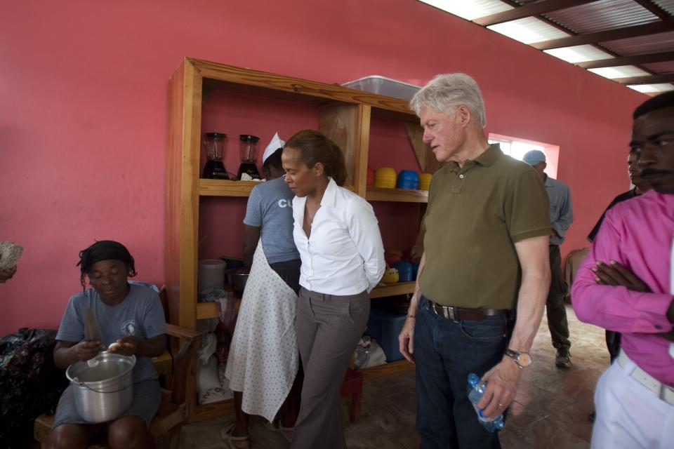 Former U.S. President and UN special envoy to Haiti Bill Clinton and Caroline Sada of Ayiti Natives, walk through the kitchen of the Union Des Apotres – Prodev School in Cite Soleil, Port-au-Prince, Haiti, Monday Feb. 17, 2014. Clinton is in Haiti to visit several projects that focus on agriculture and the environment, including the Union Des Apotres – Prodev solar-powered school that his private foundation has assisted and a training school for Haitian coffee farmers. (AP Photo/Dieu Nalio Chery)