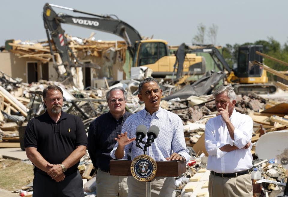 Amid the wreckage, U.S. President Barack Obama speaks as he visits the tornado devastated town of Vilonia, Arkansas May 7, 2014. With Obama are Vilonia Mayor James Firestone (L) Senator Mark Pryor (2nd L) and Governor Mike Beebe (R). The tornadoes were part of a storm system that blew through the Southern and Midwestern United States earlier this week, killing at least 35 people, including 15 in Arkansas. Obama has already declared a major disaster in Arkansas and ordered federal aid to supplement state and local recovery efforts. (REUTERS/Kevin Lamarque)