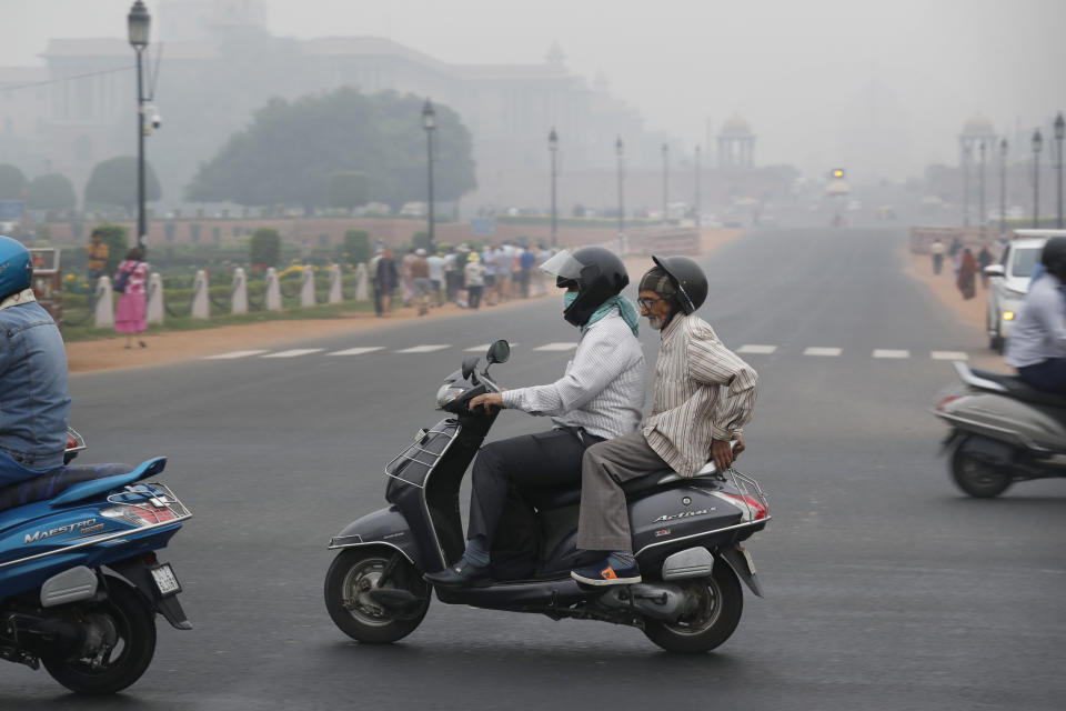 A man covers his face with a cloth and drives amidst smog in New Delhi, India, Thursday, Nov. 7, 2019. The air quality index stood at 273 on Thursday in the capital after authorities declared a health emergency last weekend when the index crossed 500 — 10 times the level considered healthy by WHO standards. (AP Photo/Manish Swarup)