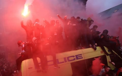 Liverpool fans sit on top of a police van - Credit: Peter Byrne/PA