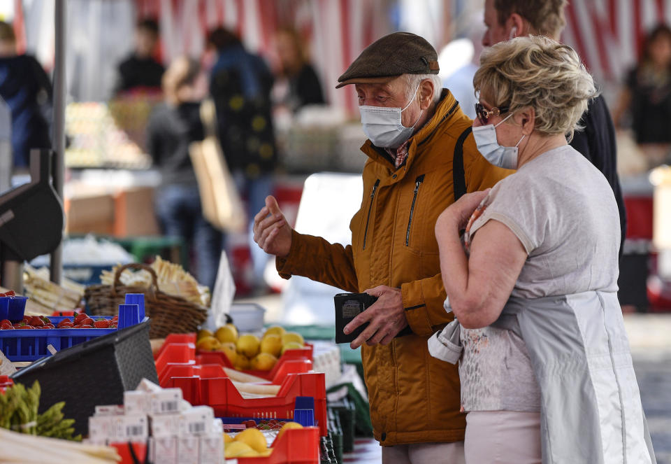Elderly people with a face mask to protect from the coronavirus go shopping at a market in Aachen, Germany, Thursday, April 9, 2020. In order to slow down the spread of the coronavirus, the German government has considerably restricted public life and asked for social distancing. The new coronavirus causes mild or moderate symptoms for most people, but for some, especially older adults and people with existing health problems, it can cause more severe illness or death. (AP Photo/Martin Meissner)